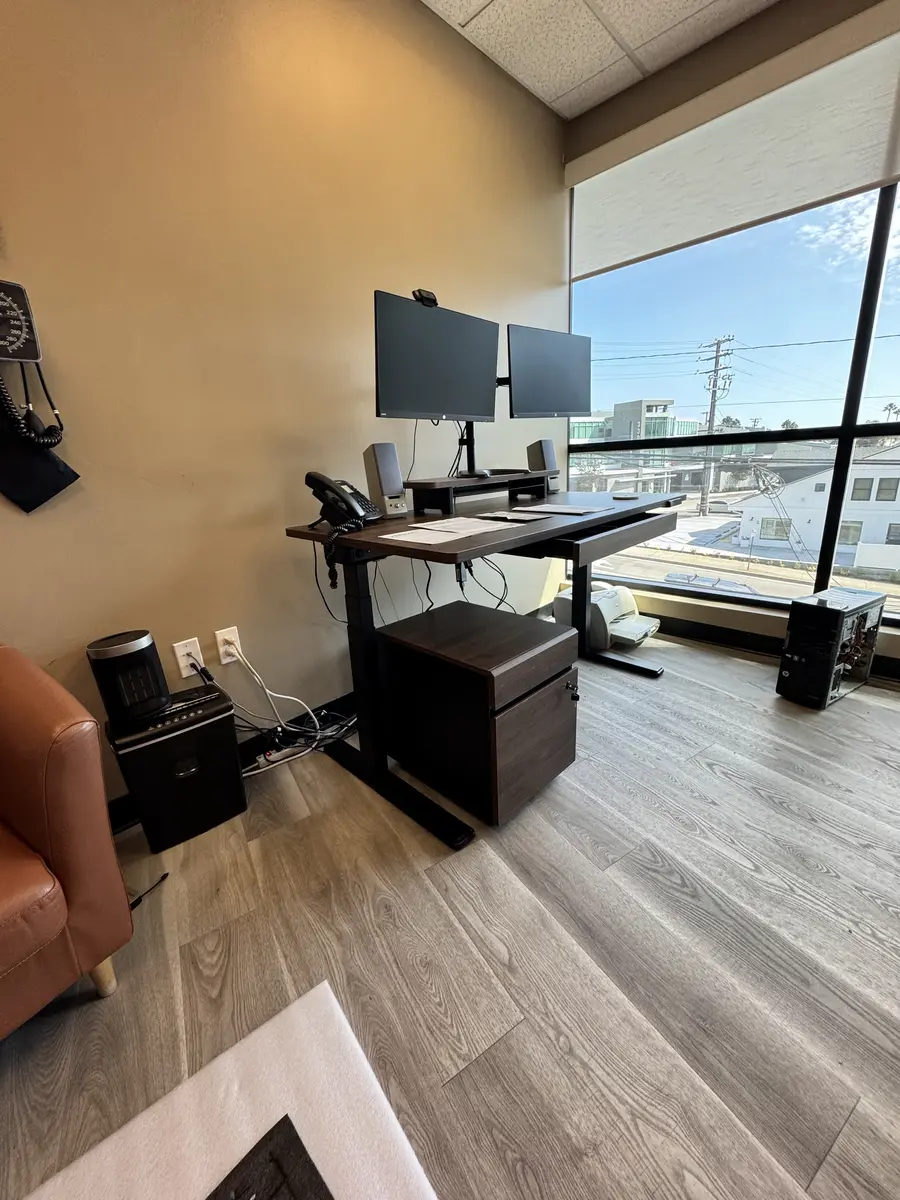 Sit-stand desk with dual monitor arm assembled in an Orange County office